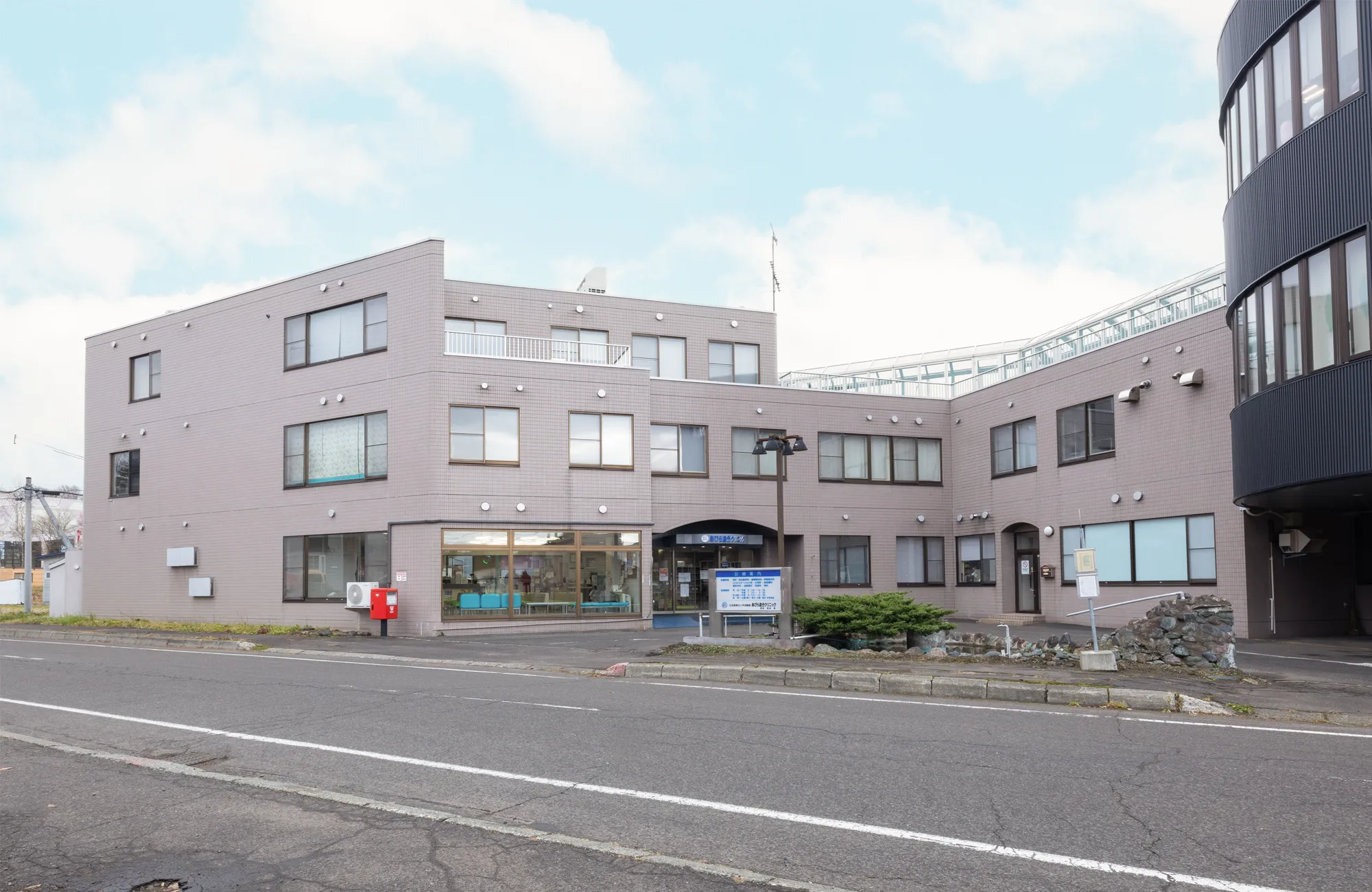 介護施設の建物外観。ベージュ色の壁面、複数階建て、入口に案内表示。